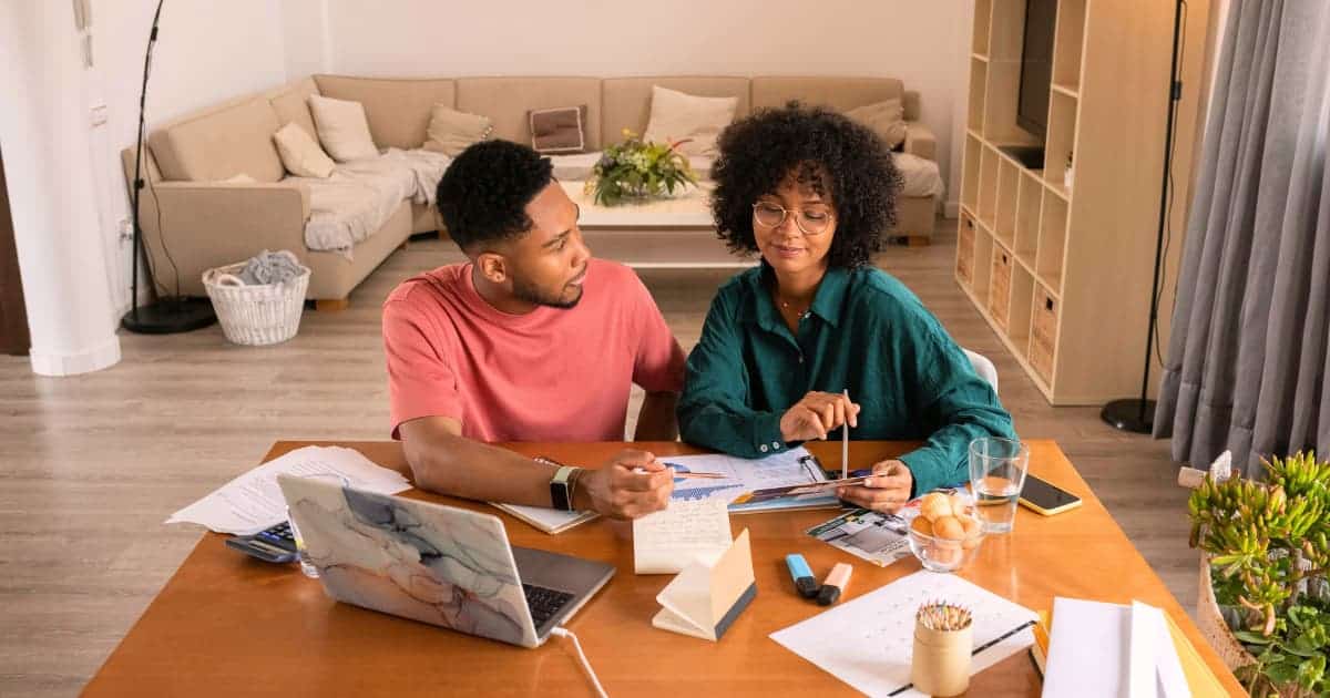 Parent and student discussing financial documents at the kitchen table.