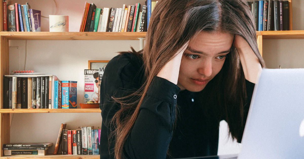 A stressed student solving physics equations on a her laptop.
