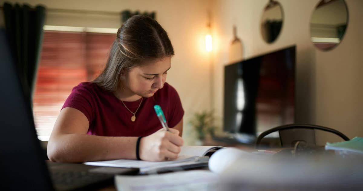 A high school student writing a college application with an additional essay page, titled "Supplemental Essay," highlighted.