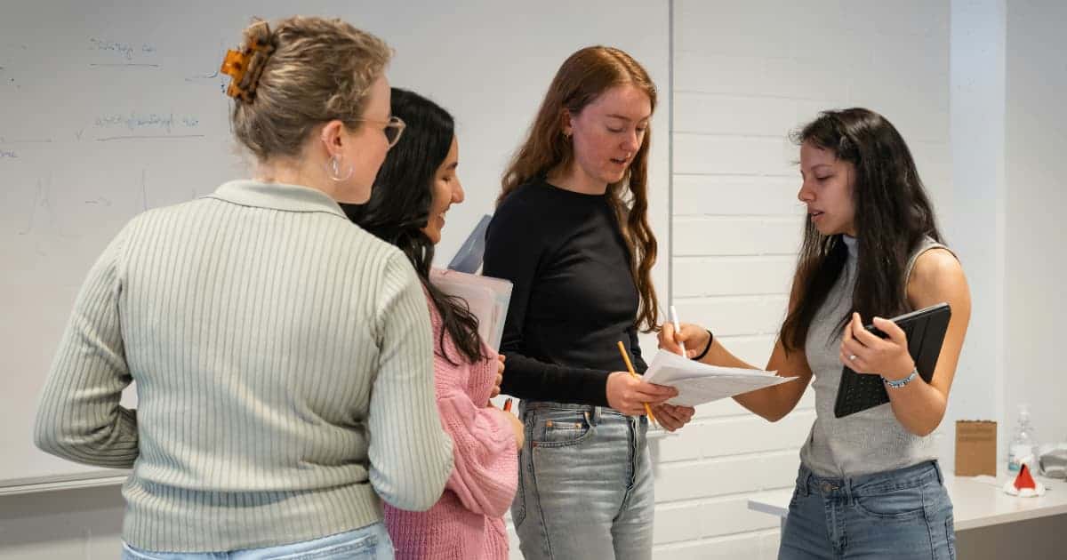 Students looking at a laptop finding out their Restrictive Early Action (REA) college application has been accepted.