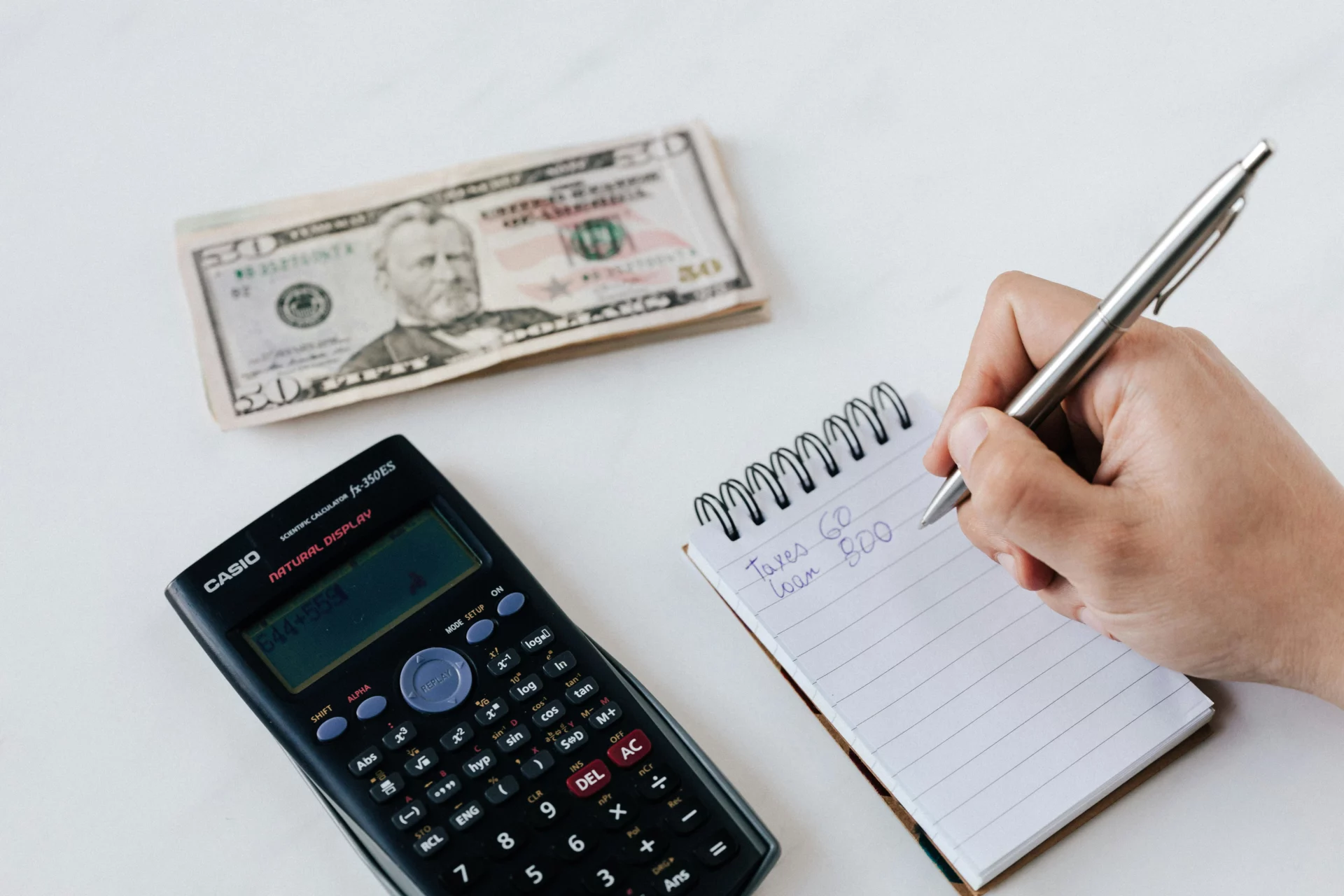 Student using a notepad and calculator to plan college savings with a 529 plan