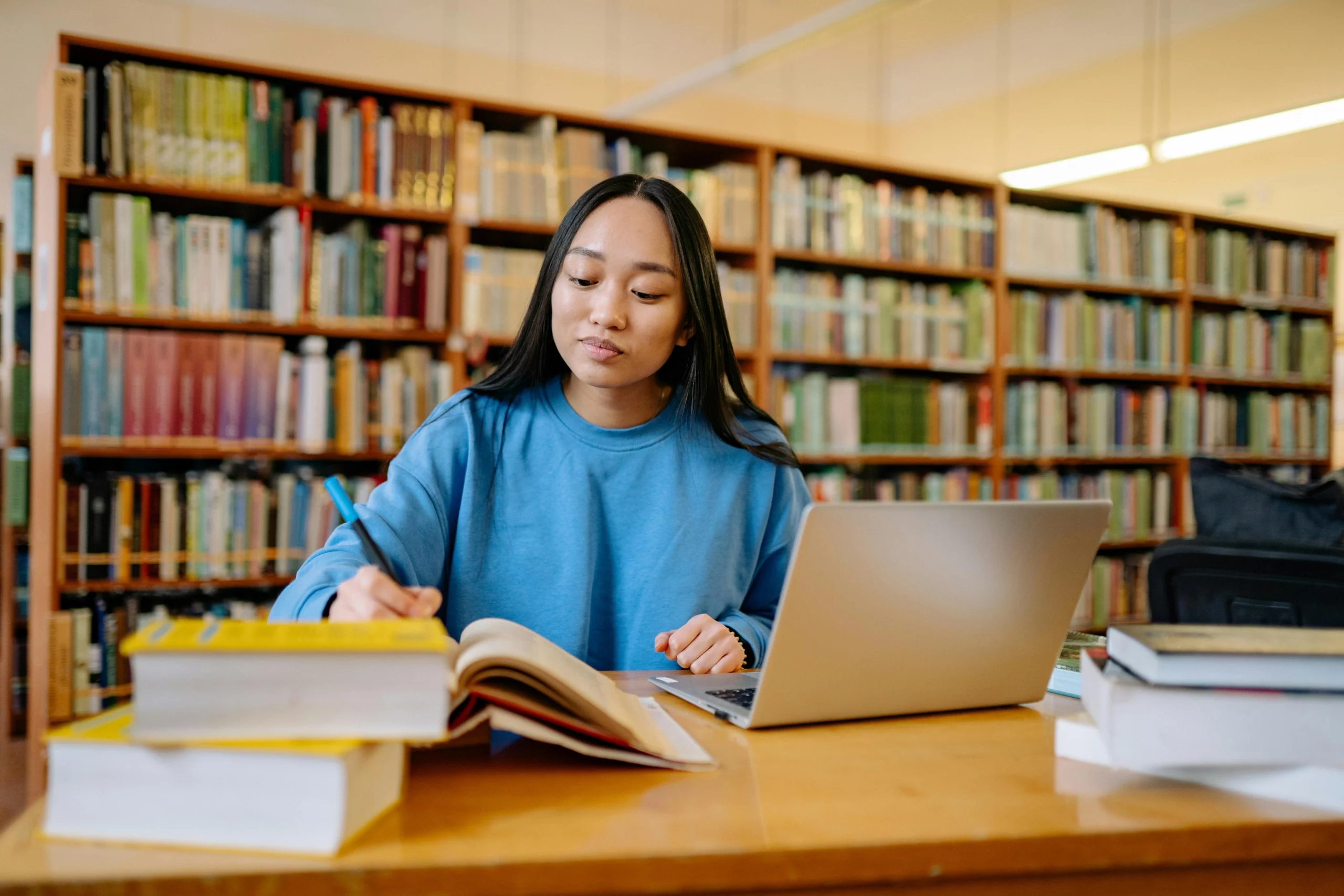 Girl studying in a library for a merit-based scholarship opportunity
