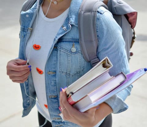 woman walking with all her books to her college