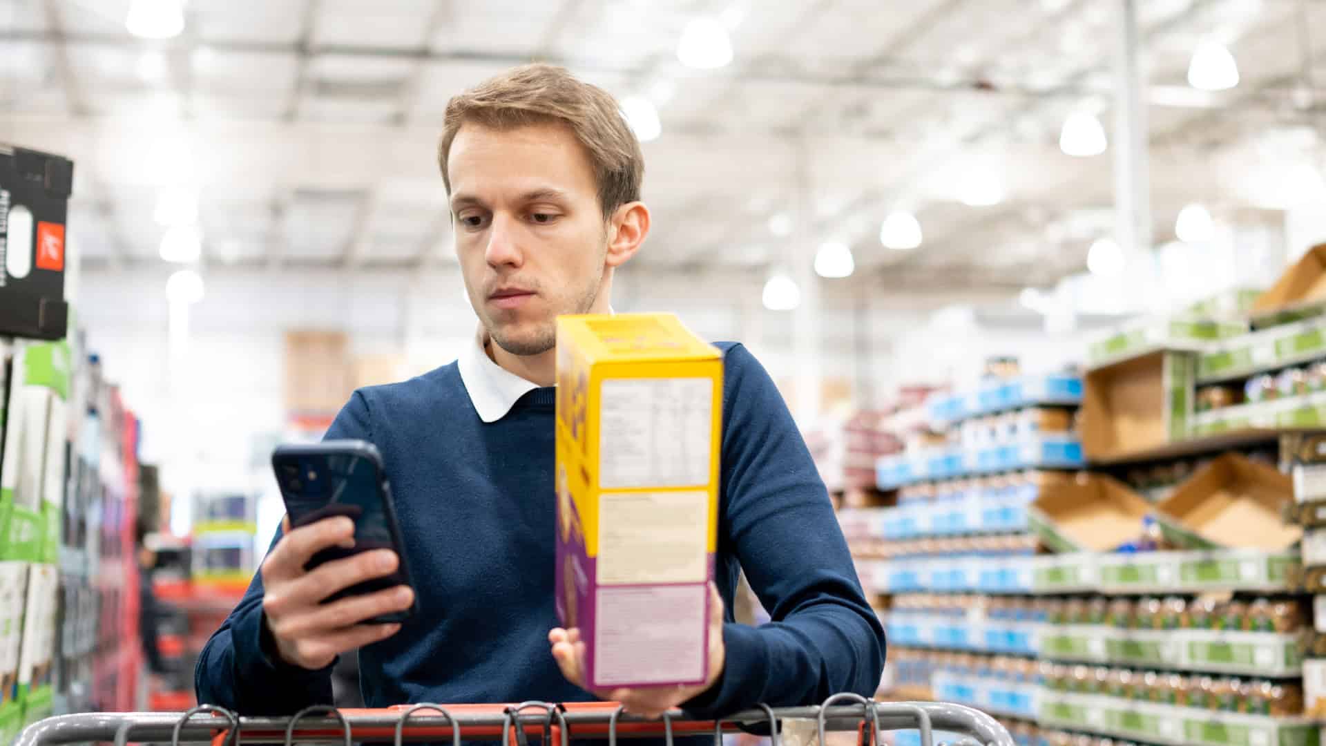 student figuring out his budget while buying groceries