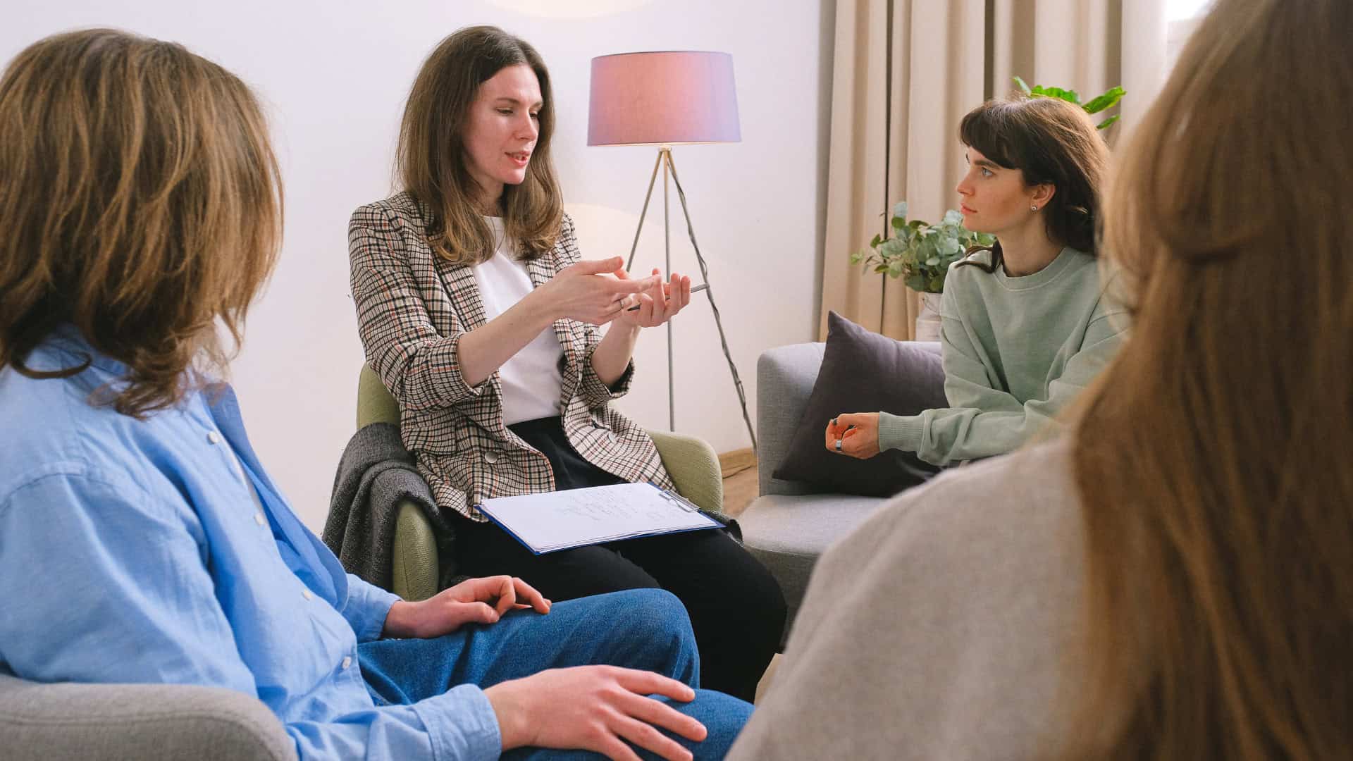group of students sitting with a counsellor discussing their problems in high school