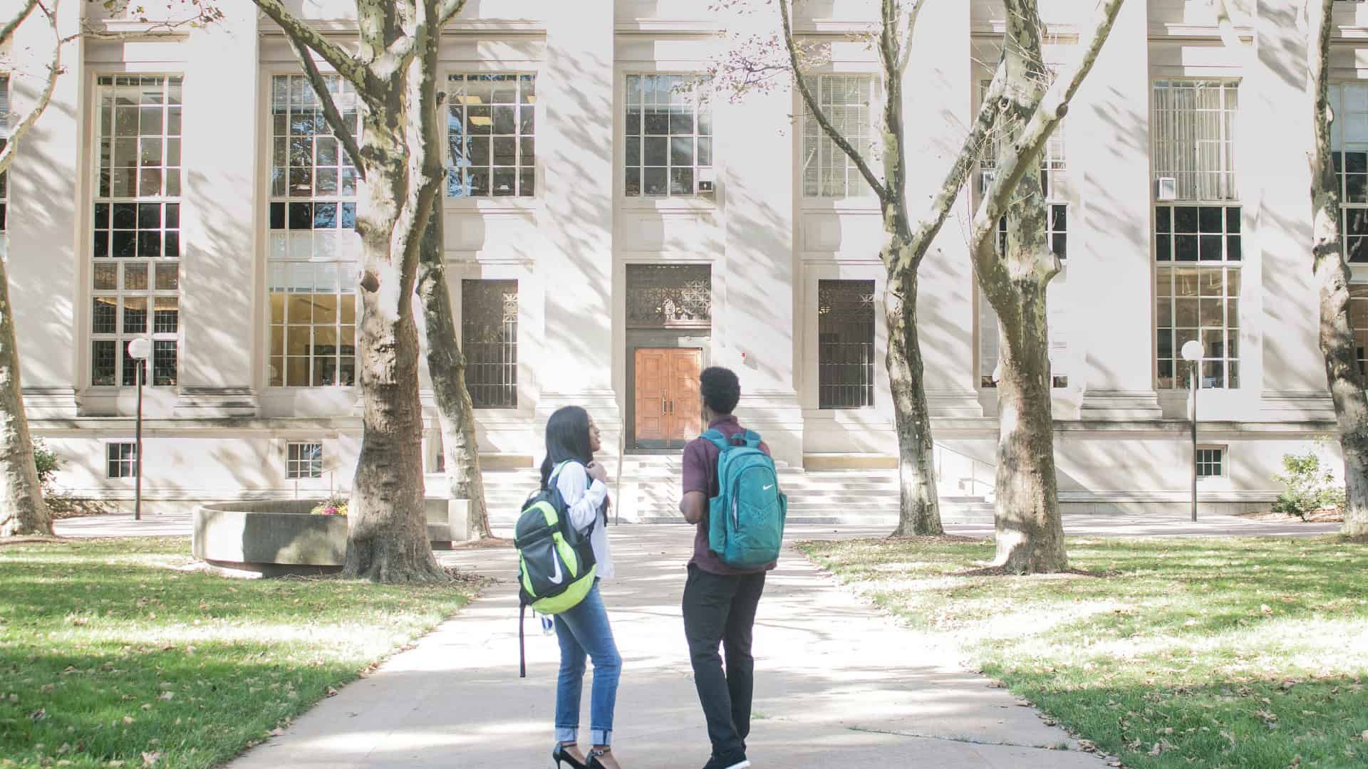 two students standing at a college campus and discussing what not to consider when choosing your college