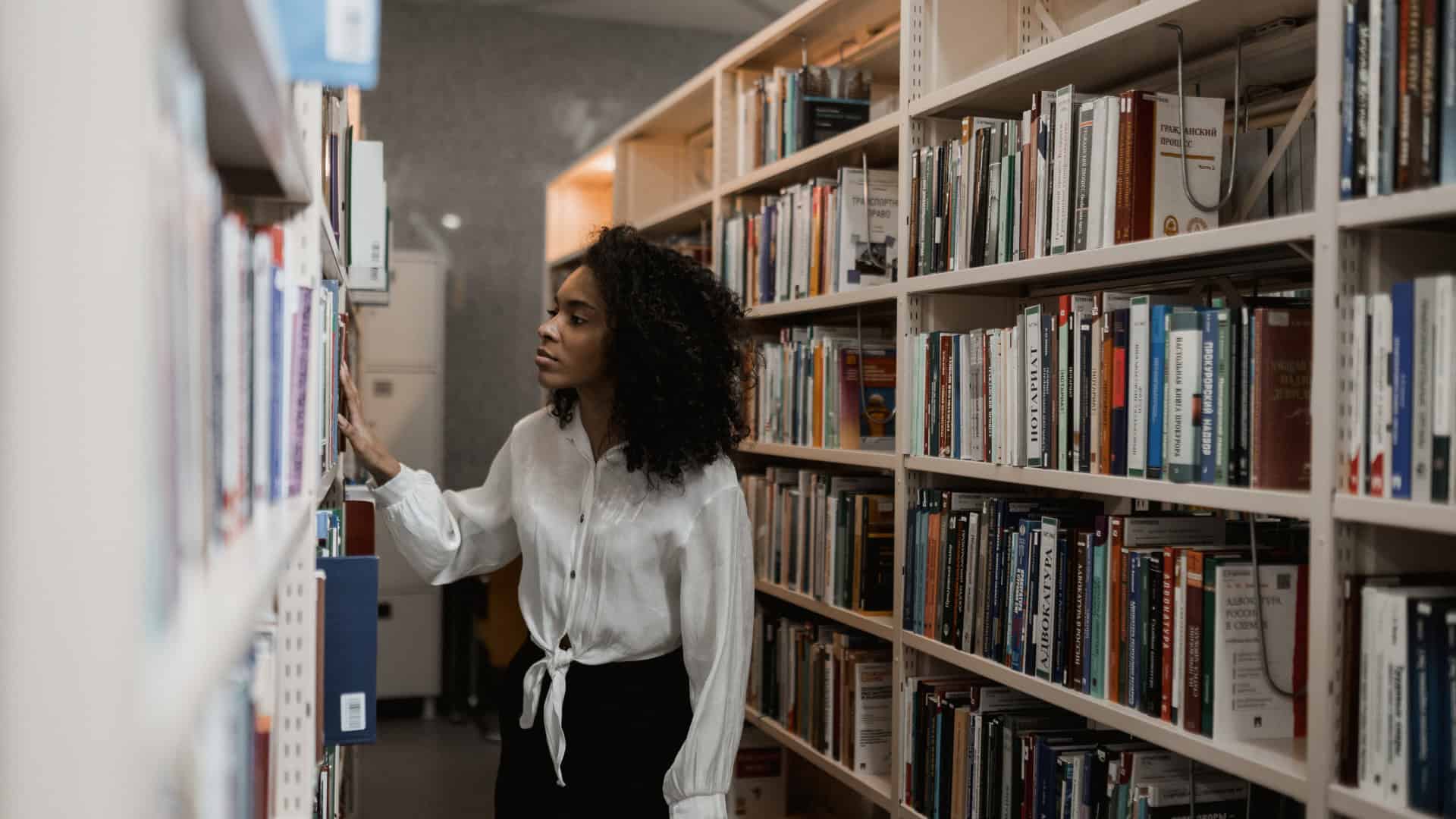 a students in a library looking through different courses while starting her college search