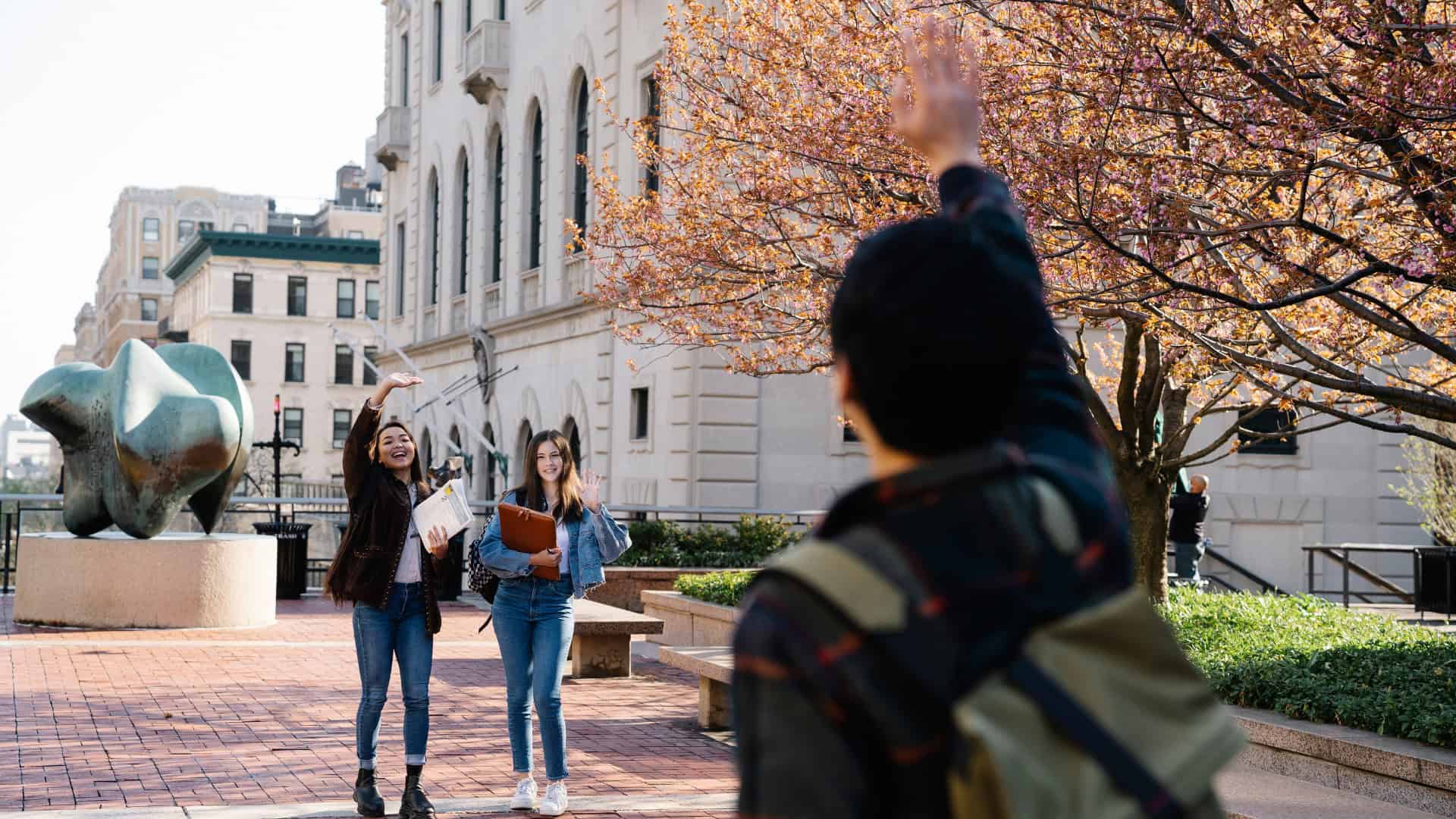 three students waving to each other and discussing the different types of colleges in the us